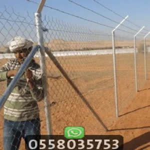 عمال مؤسسة العالم الجميل أثناء عملية تركيب شبوك مزارع مجلفنة في جدة بقواعد خرسانية قوية.